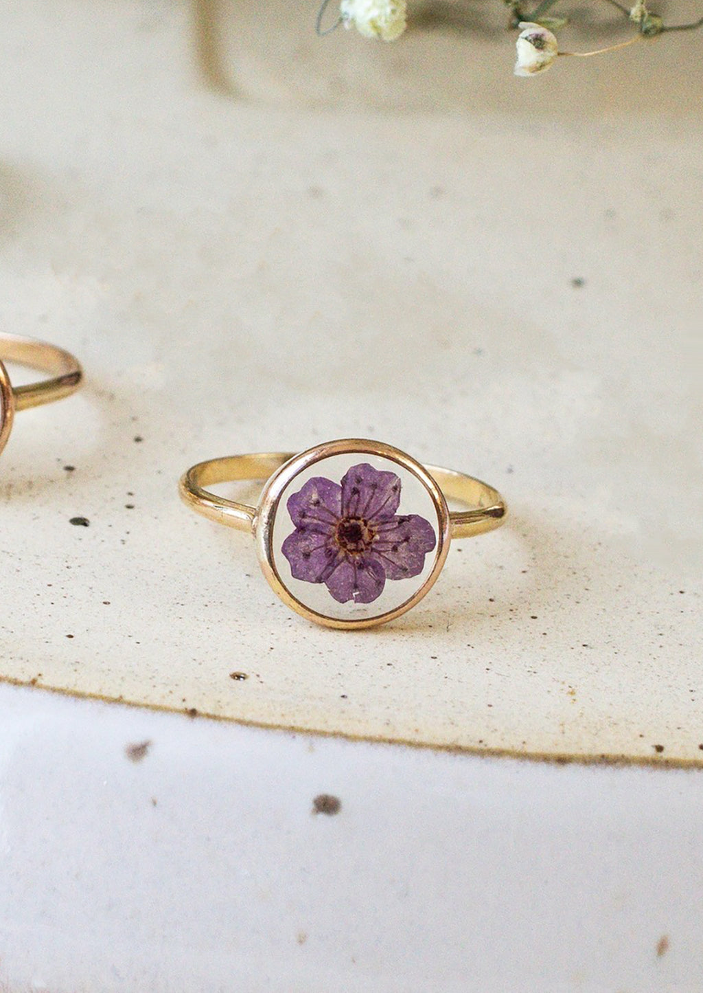 Size 5 / Purple: A gold round bezel ring showing purple flower on clear background.