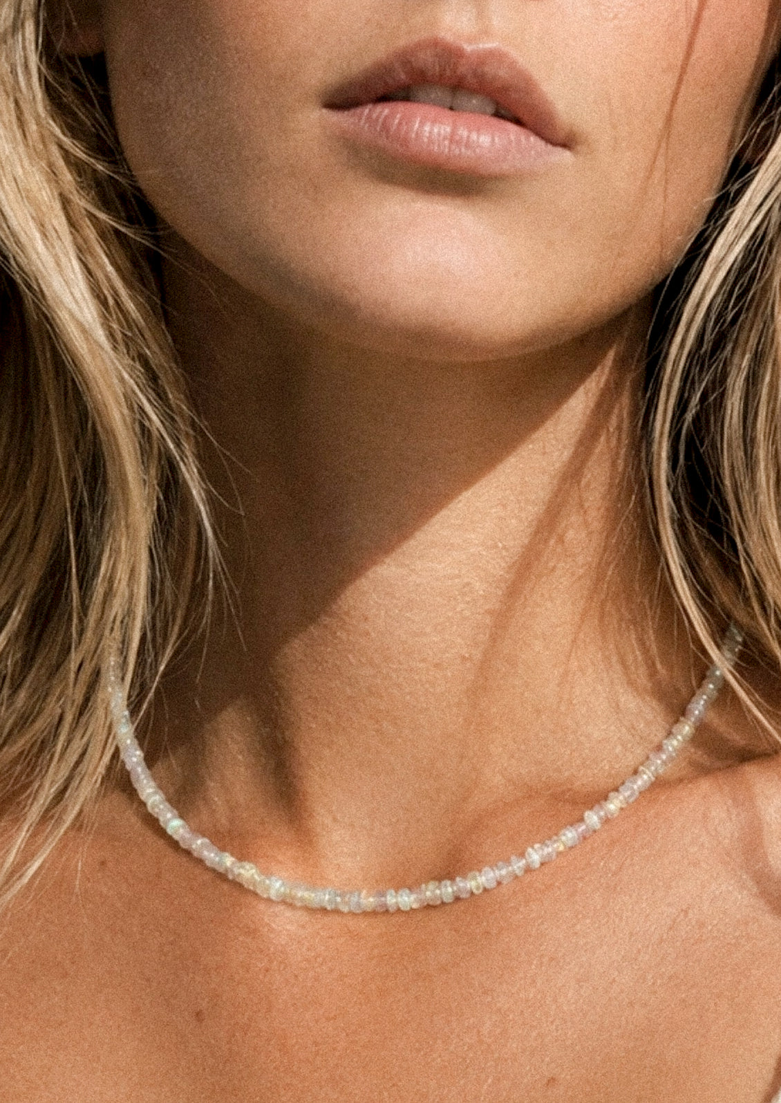 A woman wearing a beaded opal necklace.