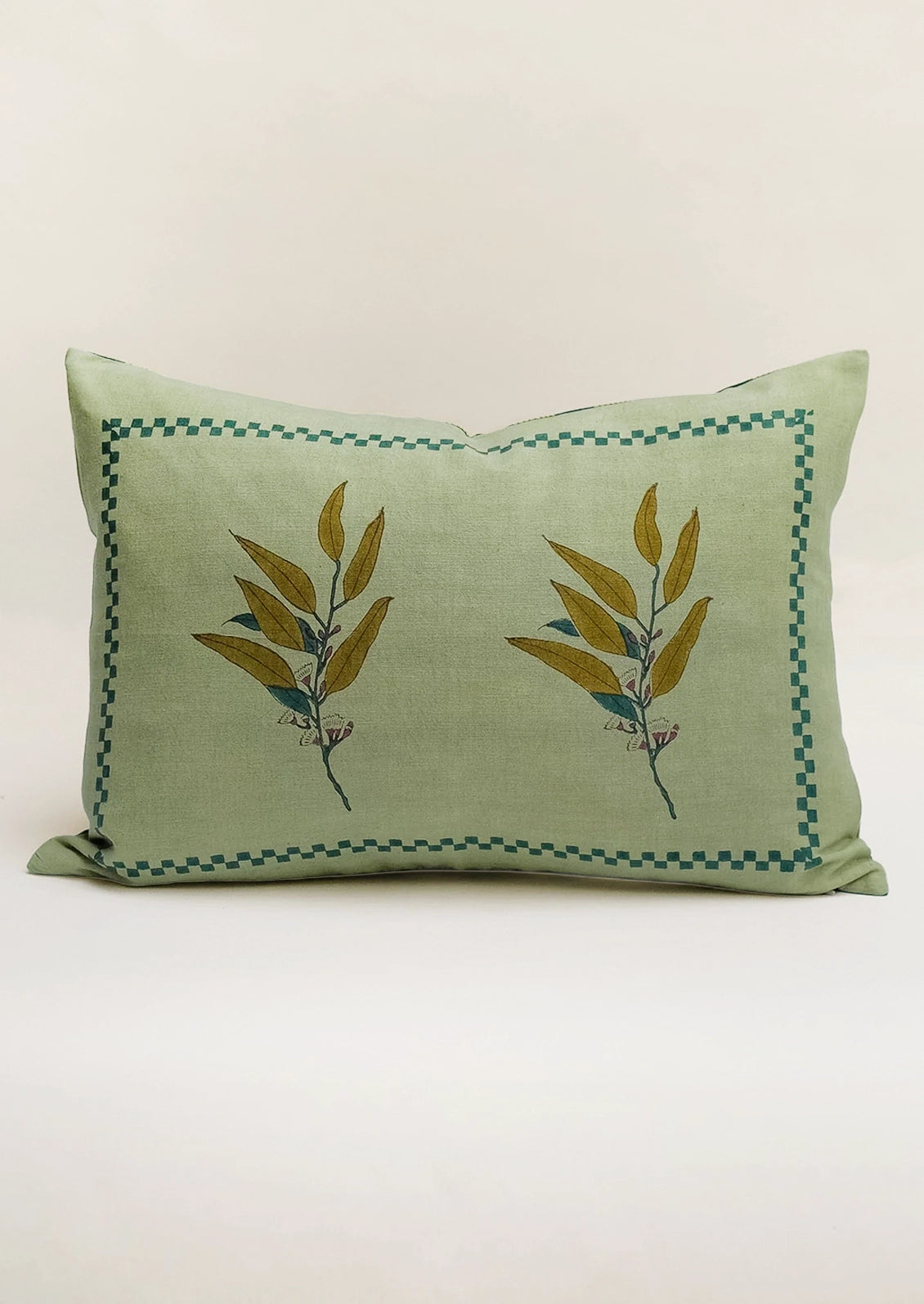 A lumbar pillow in green with eucalyptus motif.