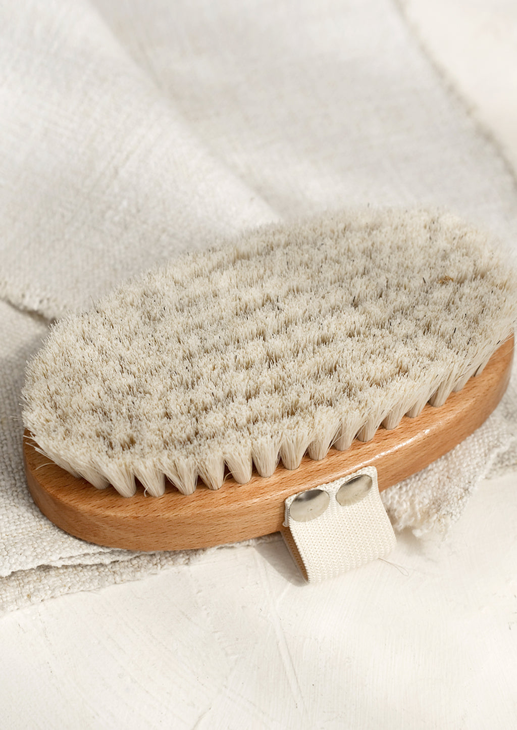 1: An oval shaped wood and bristle bath brush with elastic hand strap.