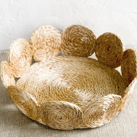 Natural / Small: A round, shallow basket with woven circular border design in natural.