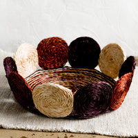Fig Multi / Small: A round, shallow basket with woven circular border design in fig multi.