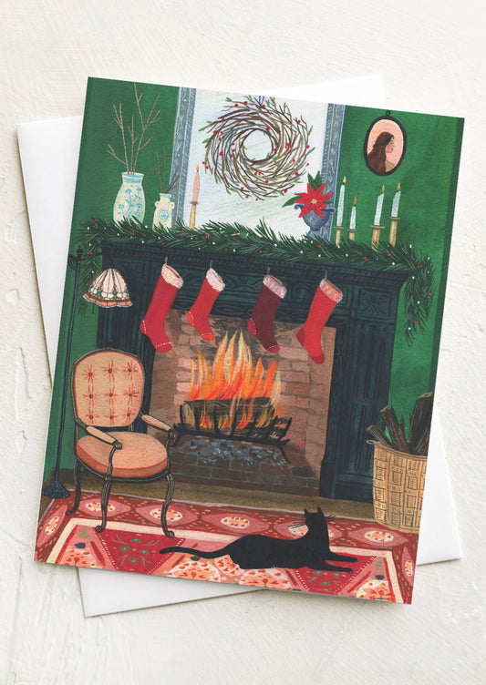 Christmas card with a fireplace, stockings, and a cat on a red rug.