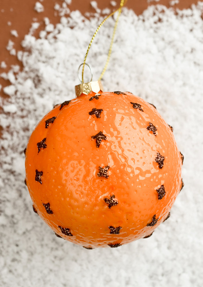 A glass ornament of a clove spiked orange.