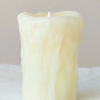 2: A flameless electronic pillar candle in natural color with drippy appearance.
