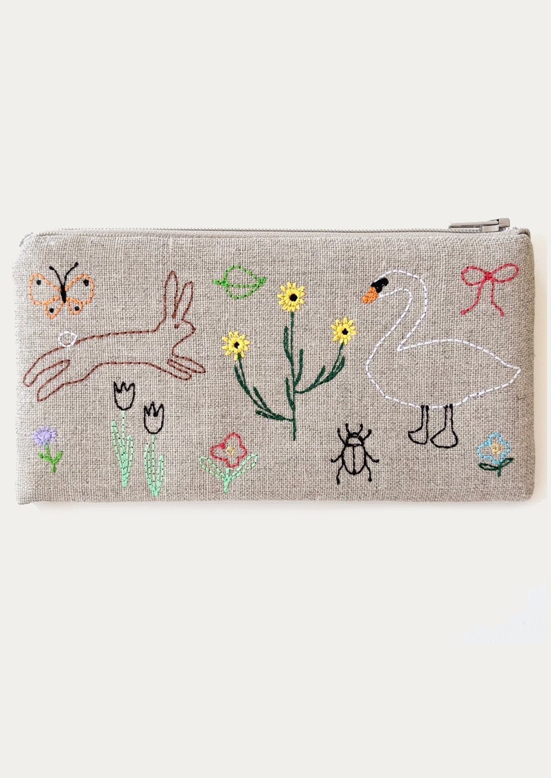 Embroidered pouch with animal and floral designs on a beige background