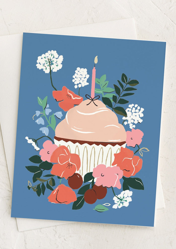 A greeting card with blue background and illustration of floral cupcake.