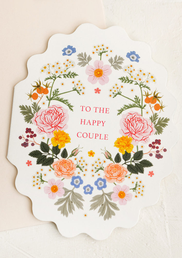 A scalloped oval shape greeting card with floral print reads "To the happy couple".