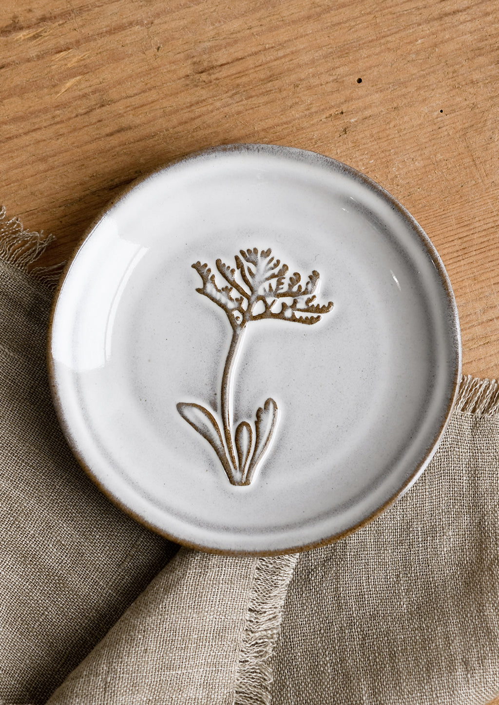 Dusty Miller: A grey glazed brown clay mini plate with raised flower design.