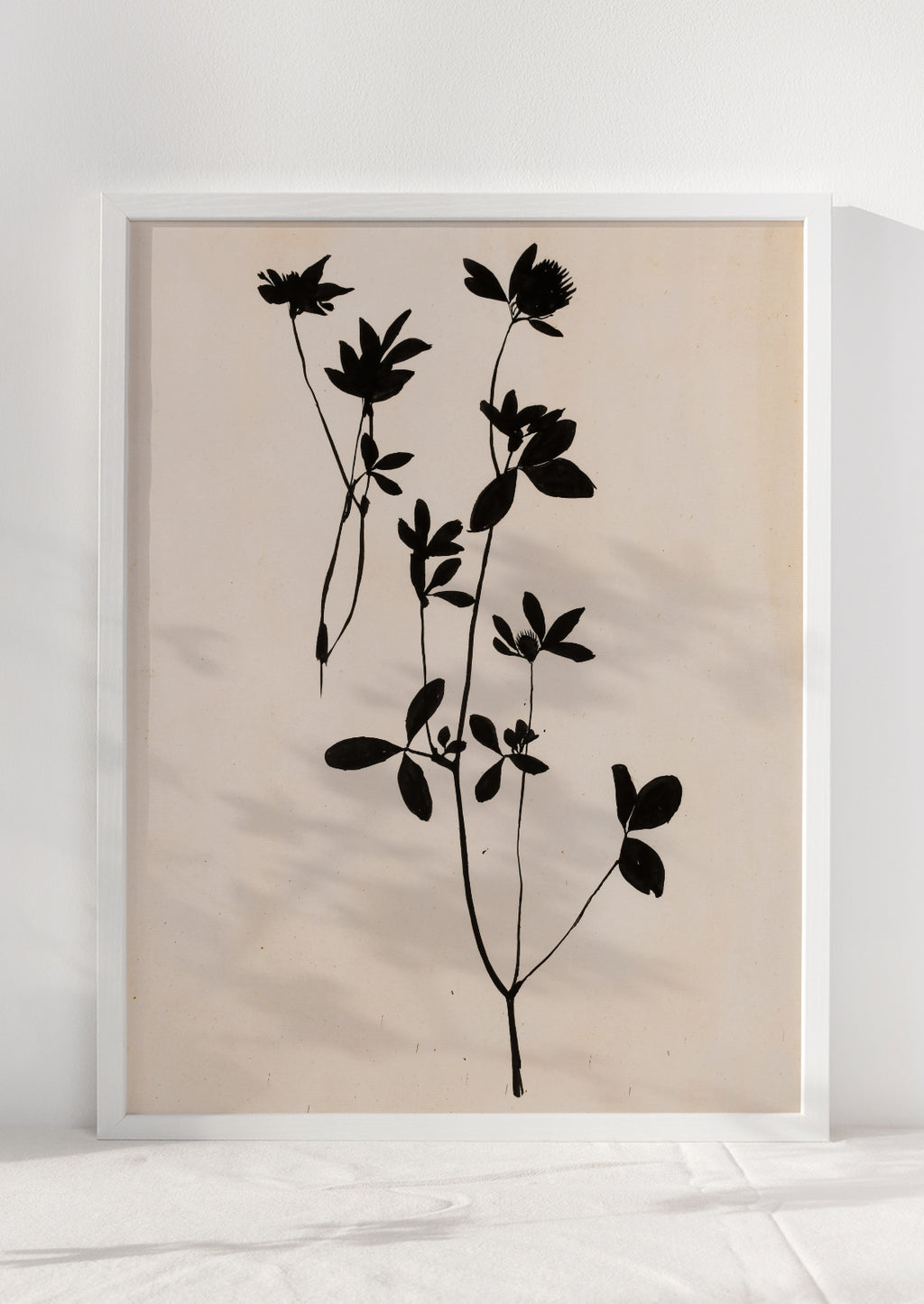 2: An art print of black silhouetted flower on beige background,framed.