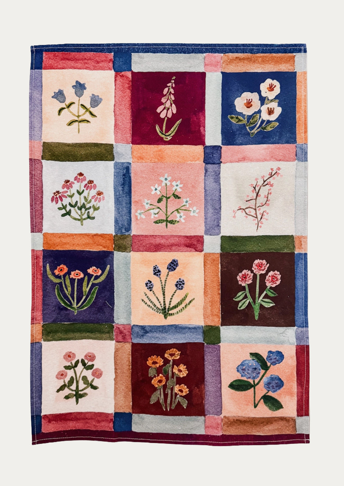 A cotton tea towel with colorful floral grid pattern.