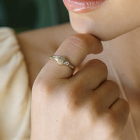 2: A gold signet ring with floral engraving with clear crystal on either side.
