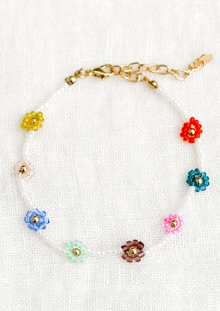 A beaded bracelet in white with mulitcolor beaded flowers.