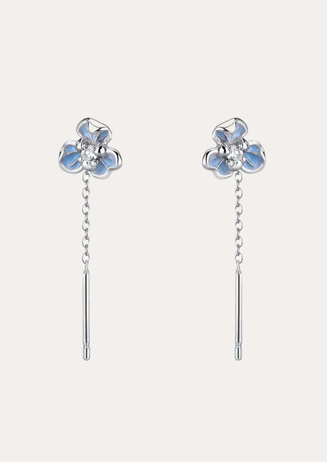 A pair of sterling silver threader earrings with blue flowers at the top on a white background.