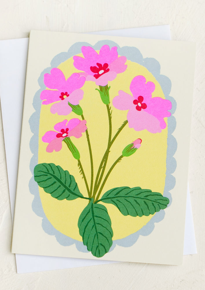 A card with image of pink flowers with blue scalloped frame border.