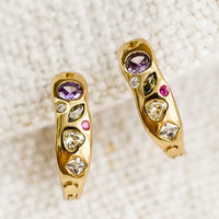 2: A pair of gold huggie hoops with embedded crystals in a mix of colors and shapes.