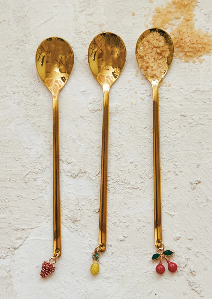 Brass finish spoons with single fruit charm at end.