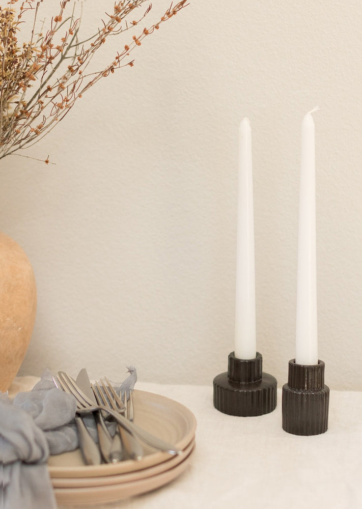 2: Black fluted taper candle holders on table scene.