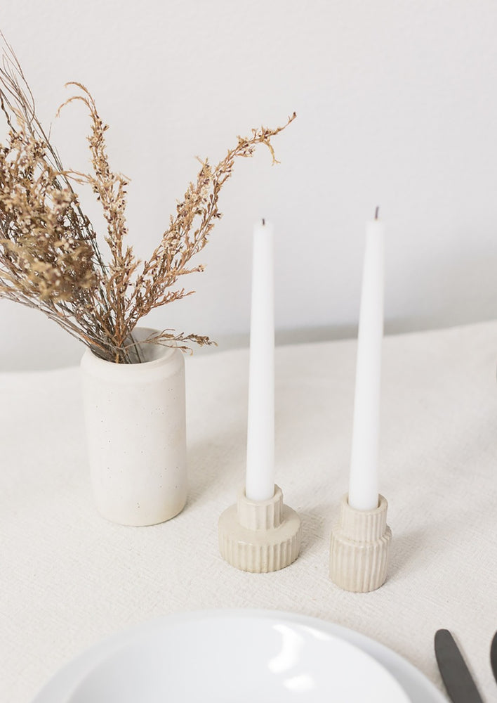 Natural fluted taper candle holders on table scene.