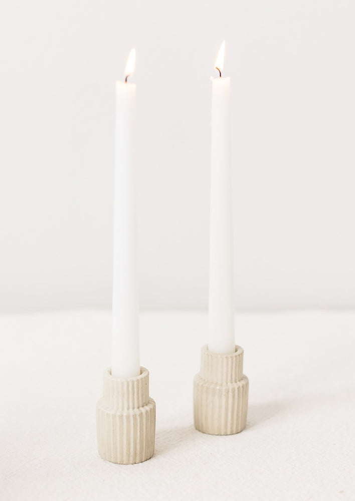 Natural fluted taper candle holders on table.