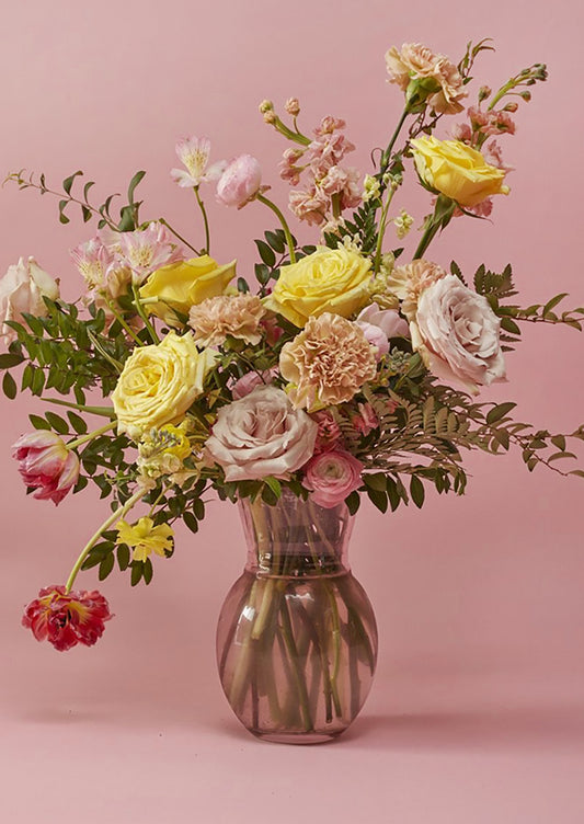 A pink tinted glass vase with pinched shape.