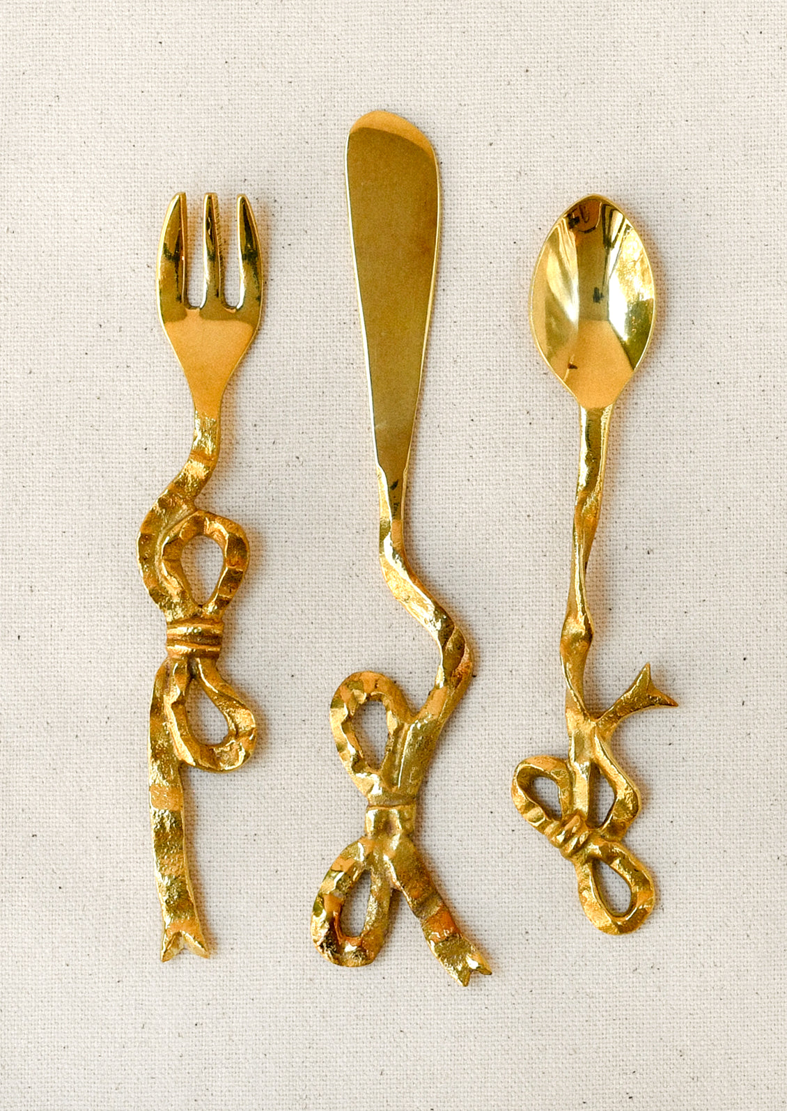Brass canapé utensils with a bow shaped design.