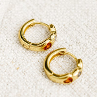 3: A pair of gold huggie hoop earrings with multicolor and multishape crystal detailing.