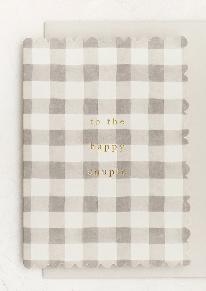 A scalloped edge card with grey gingham pattern reading "To the happy couple".