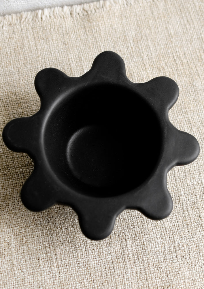 A small black ceramic bowl with splatter squiggle shape rim.