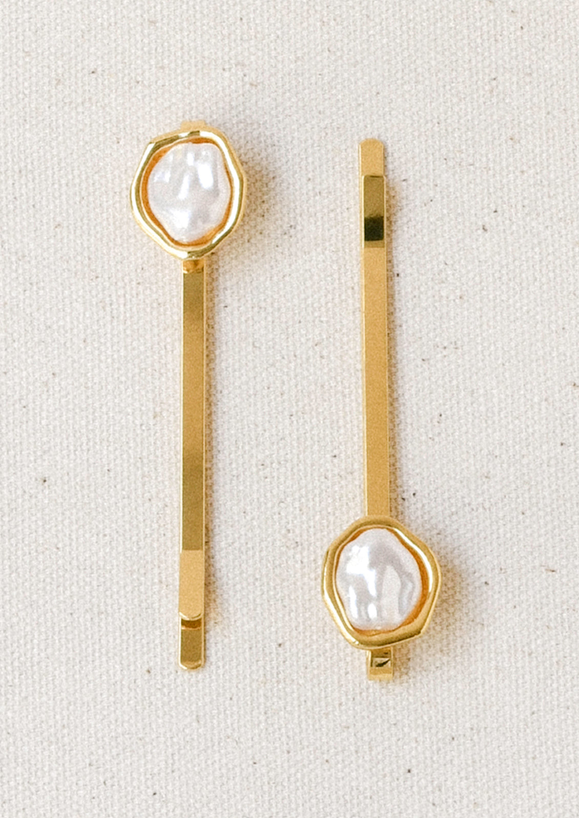 A set of 2 gold hair pins with a faux freshwater pearl on the end of each.