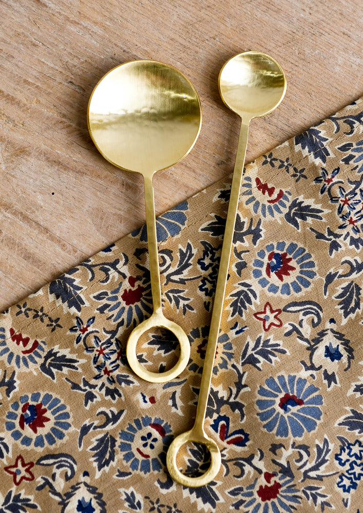 Gold finish metal spoons with circular loop at end of handle.