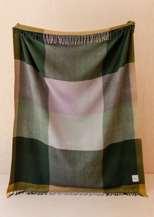 A throw blanket with colorful big check pattern in dark green, mustard and pink.