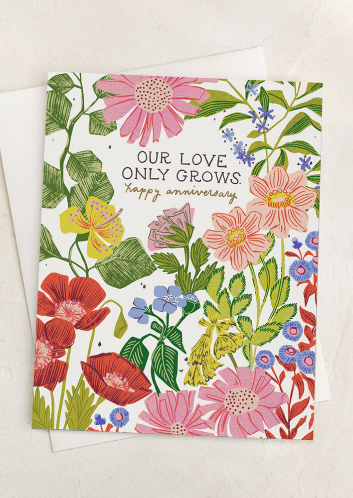 A floral print card with text reading "Our love only grows. Happy Anniversary".