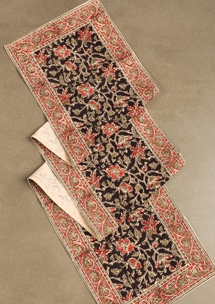1: A table runner with black and red floral print.