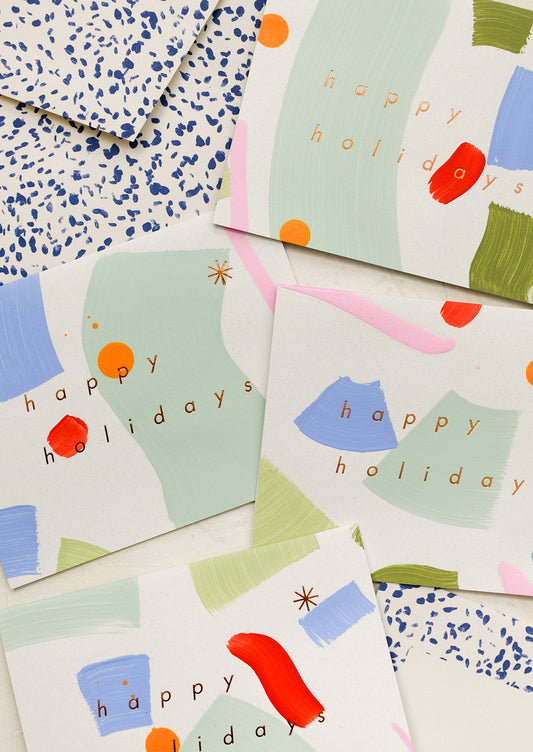 A set of multicolor hand painted cards with text reading "Happy Holidays".