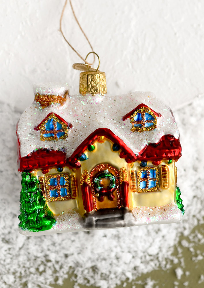 1: A glass holiday ornament of a house decorated for the holidays.