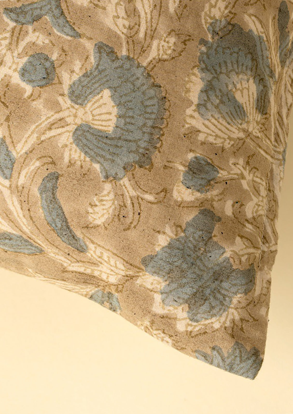 A block printed cotton throw pillow in taupe and dusty blue floral pattern.
