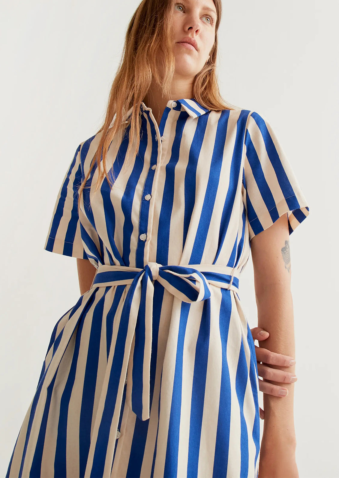 Woman wearing a blue and white striped dress against a plain background