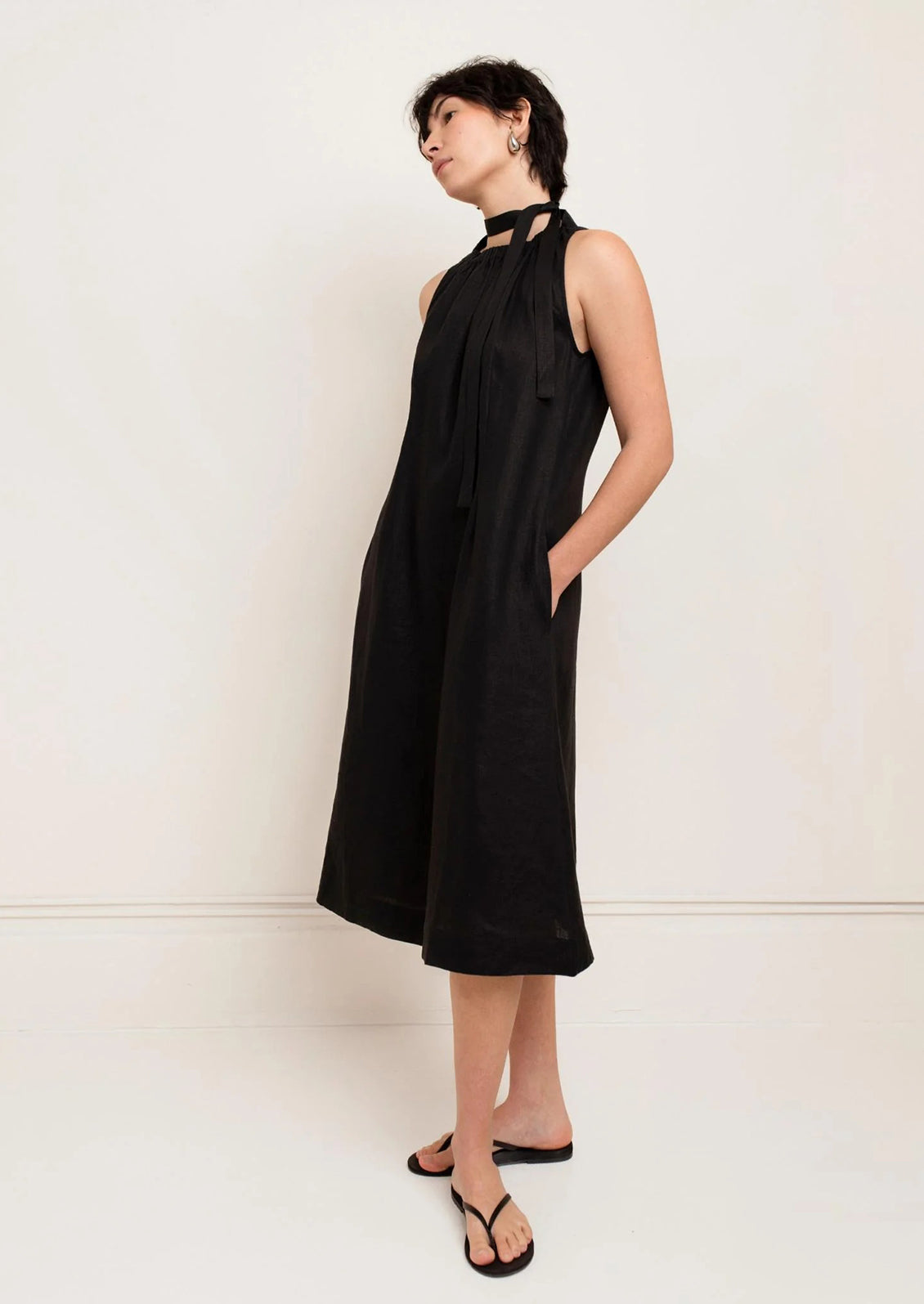 Woman wearing a black sleeveless dress against a white background