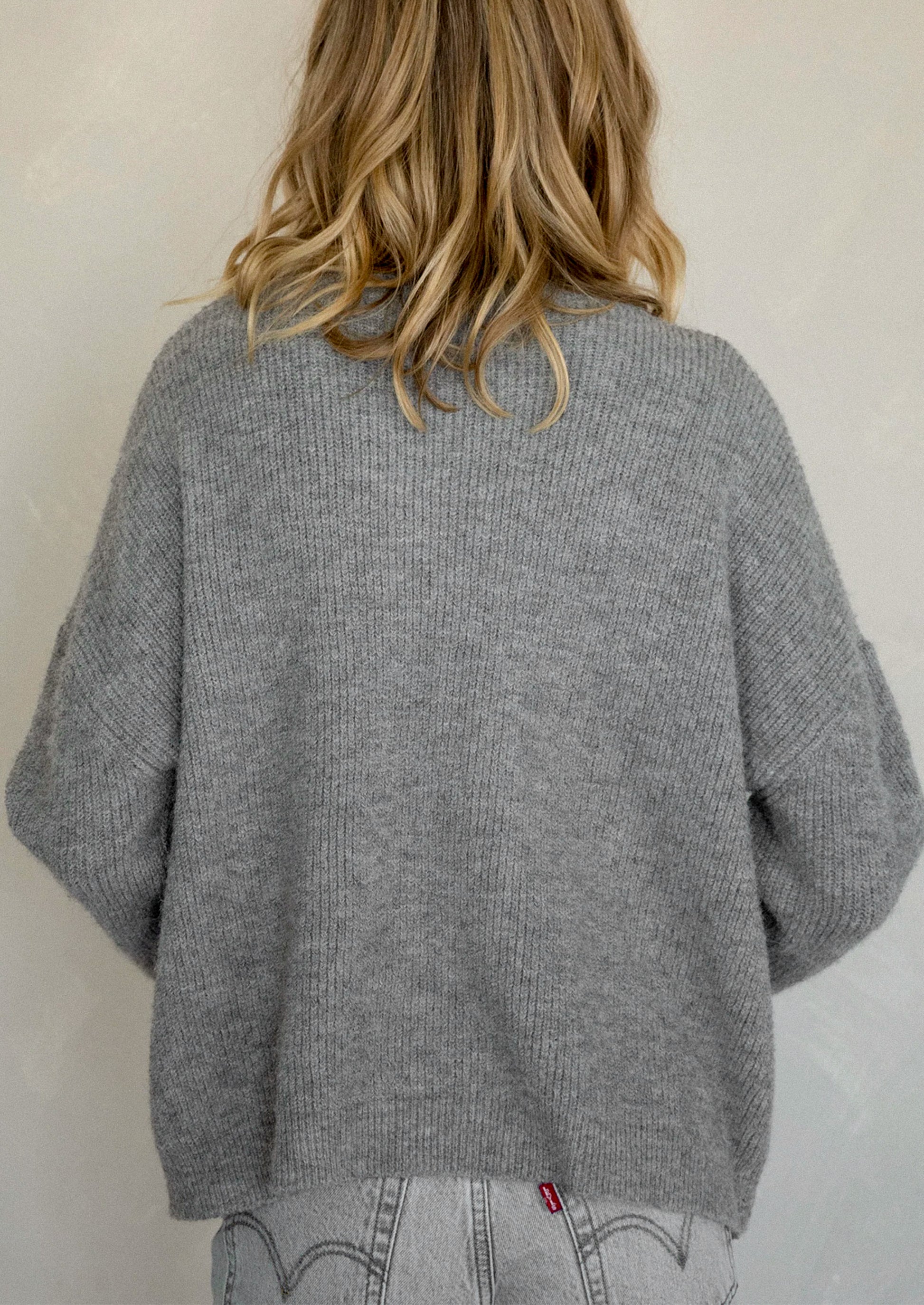 A woman wearing a heather grey cardigan sweater.