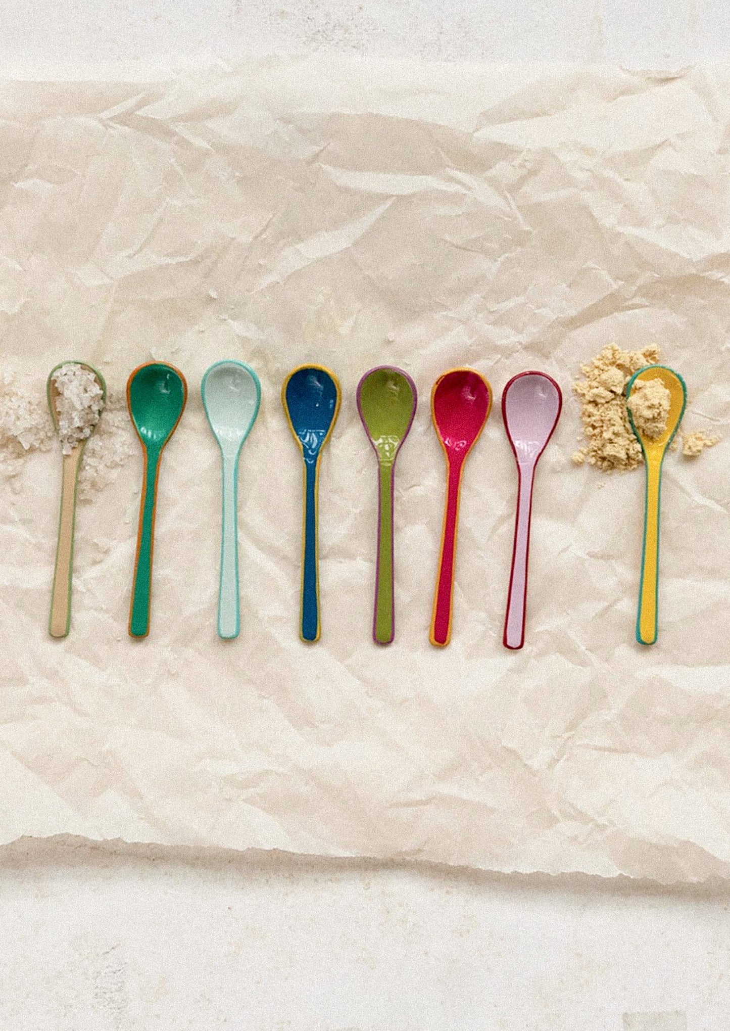 Colorful spoons arranged on a textured beige surface