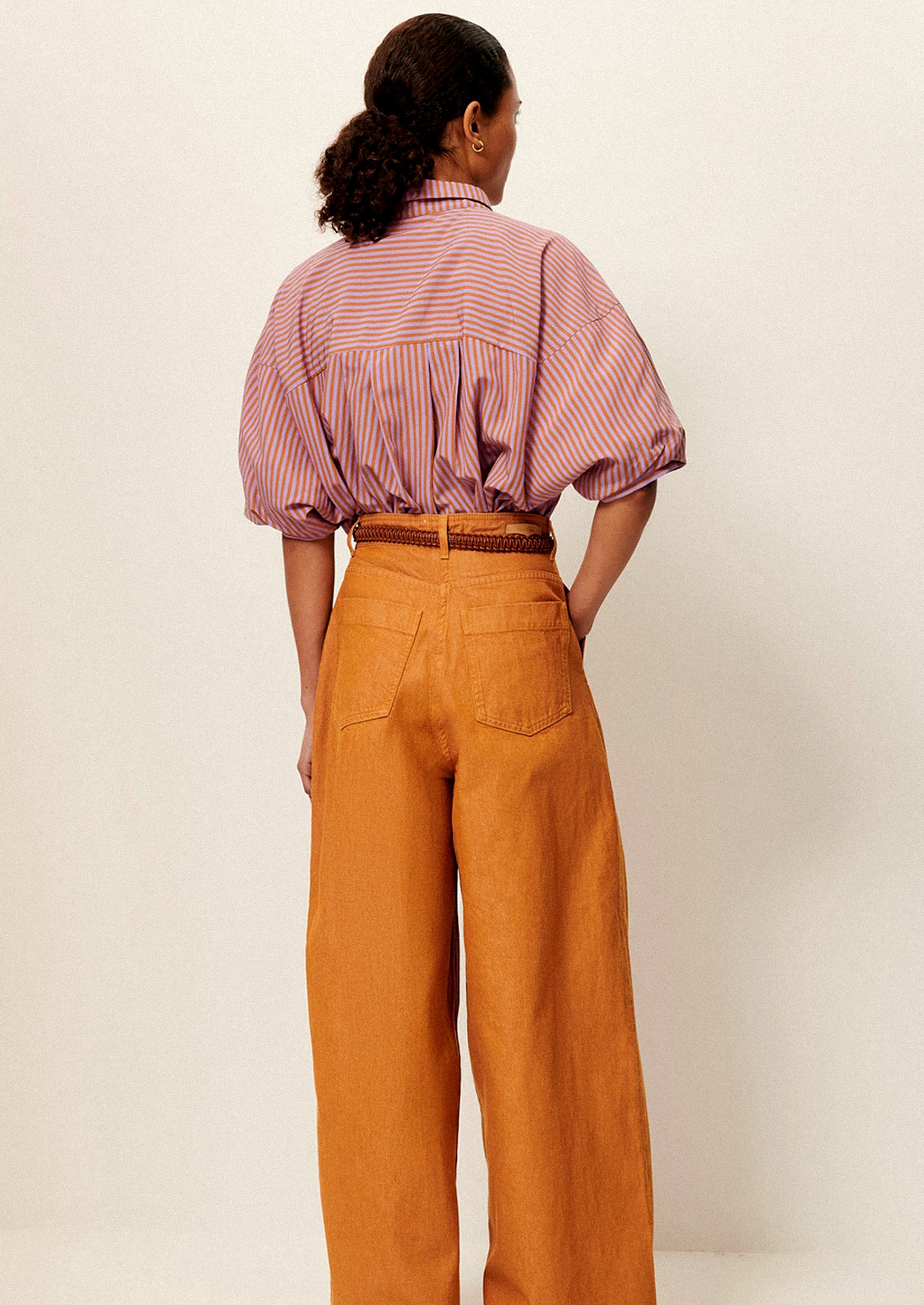 A woman wearing a short collared shirt in orange and purple stripes.