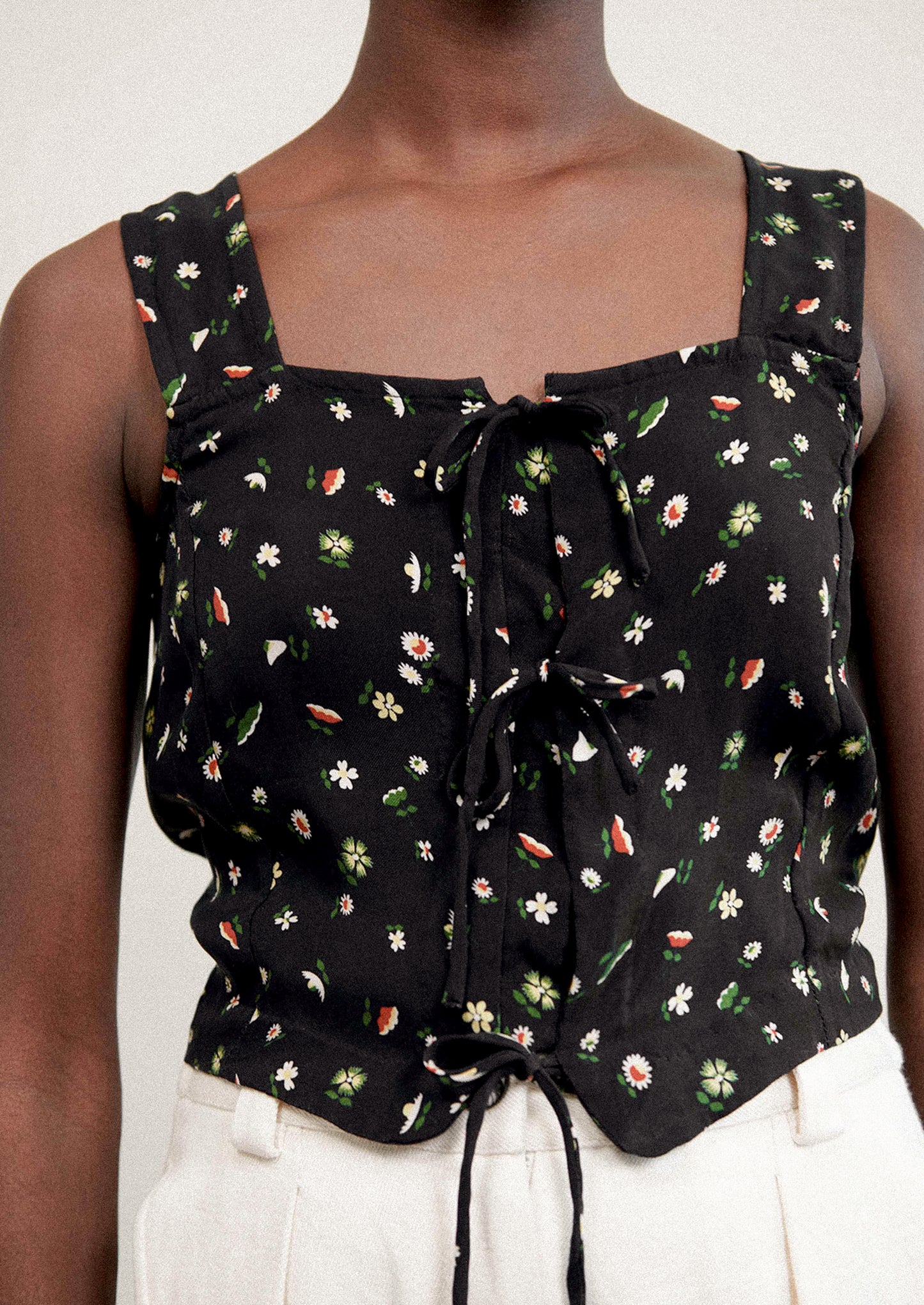 A woman wearing a black sleeveless tank top with multicolor flower print.