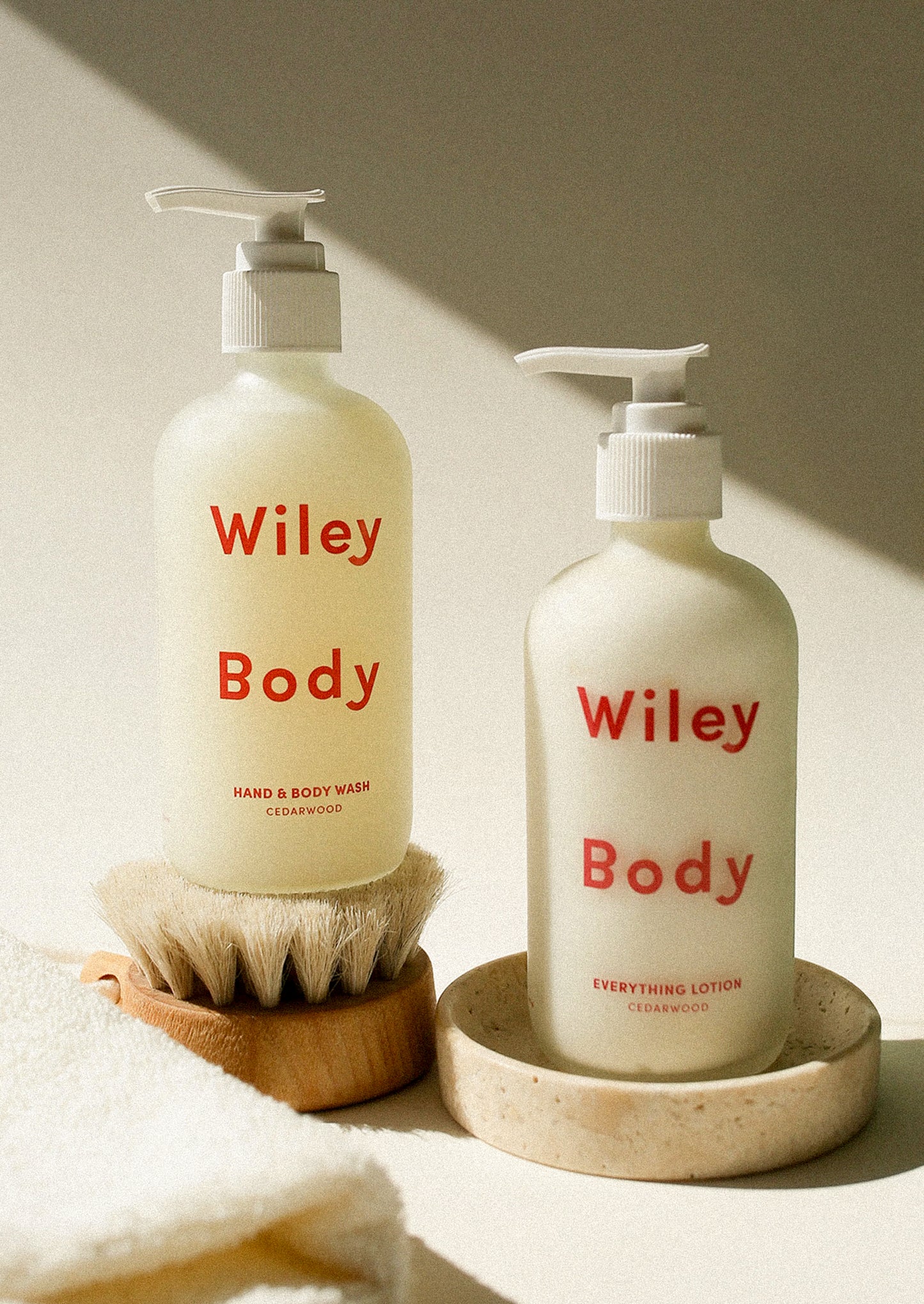 Two bottles of Wiley Body products on a neutral background