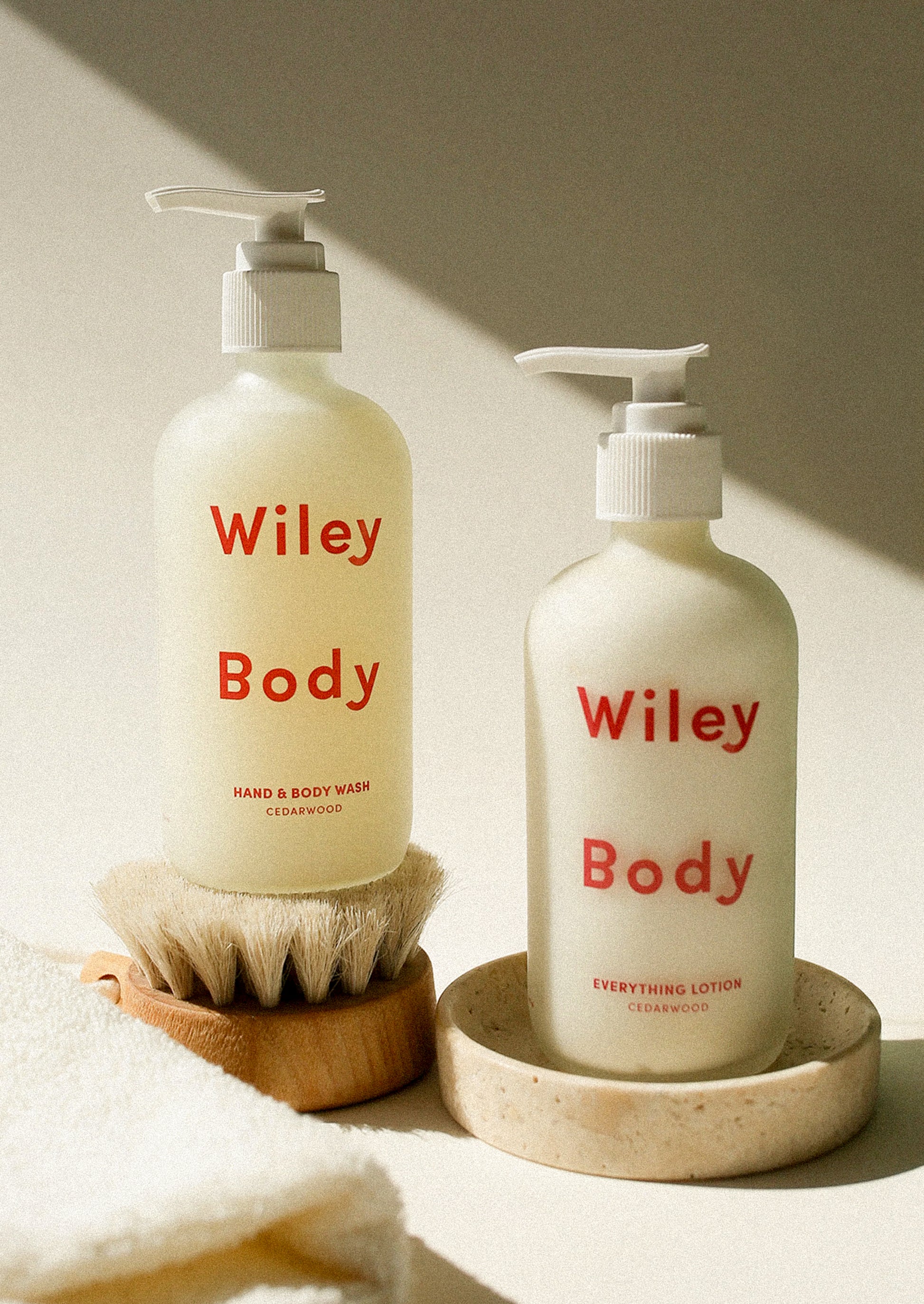 Two bottles of Wiley Body products on a neutral background