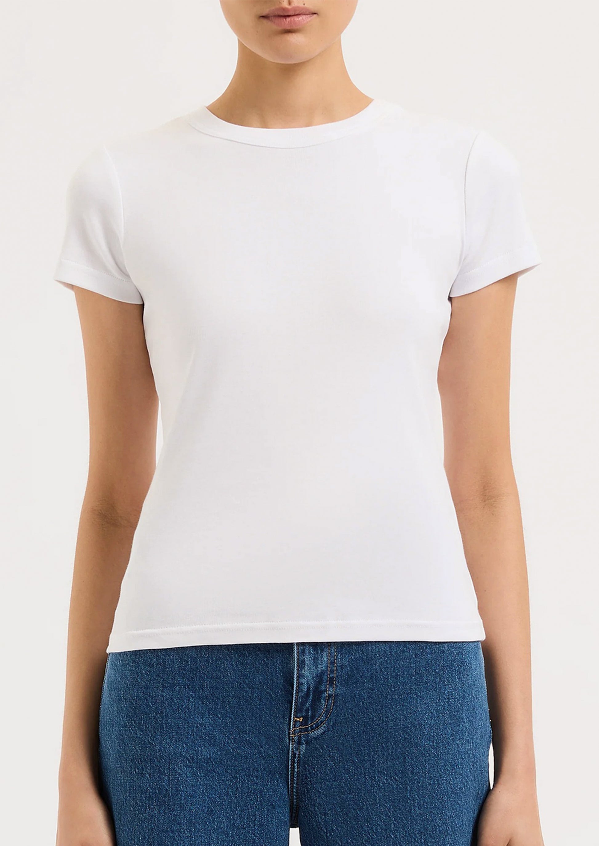 A person wearing a solid white fitted baby tee.