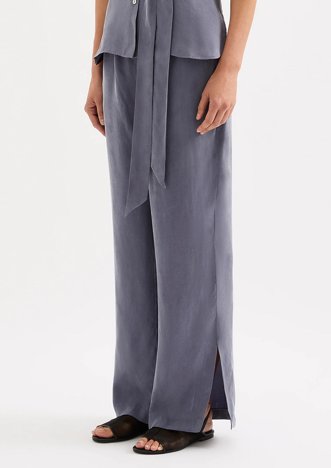 A person wearing a pair of dusty blue pants with elasticized waistband.