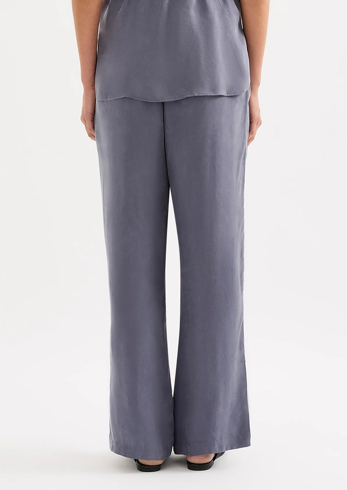 A person wearing a pair of dusty blue pants with elasticized waistband.