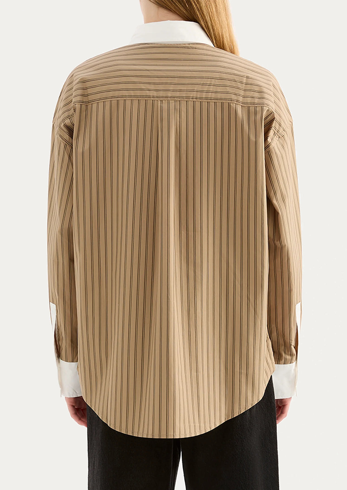 A woman wearing a beige striped shirt with white collar and cuffs.