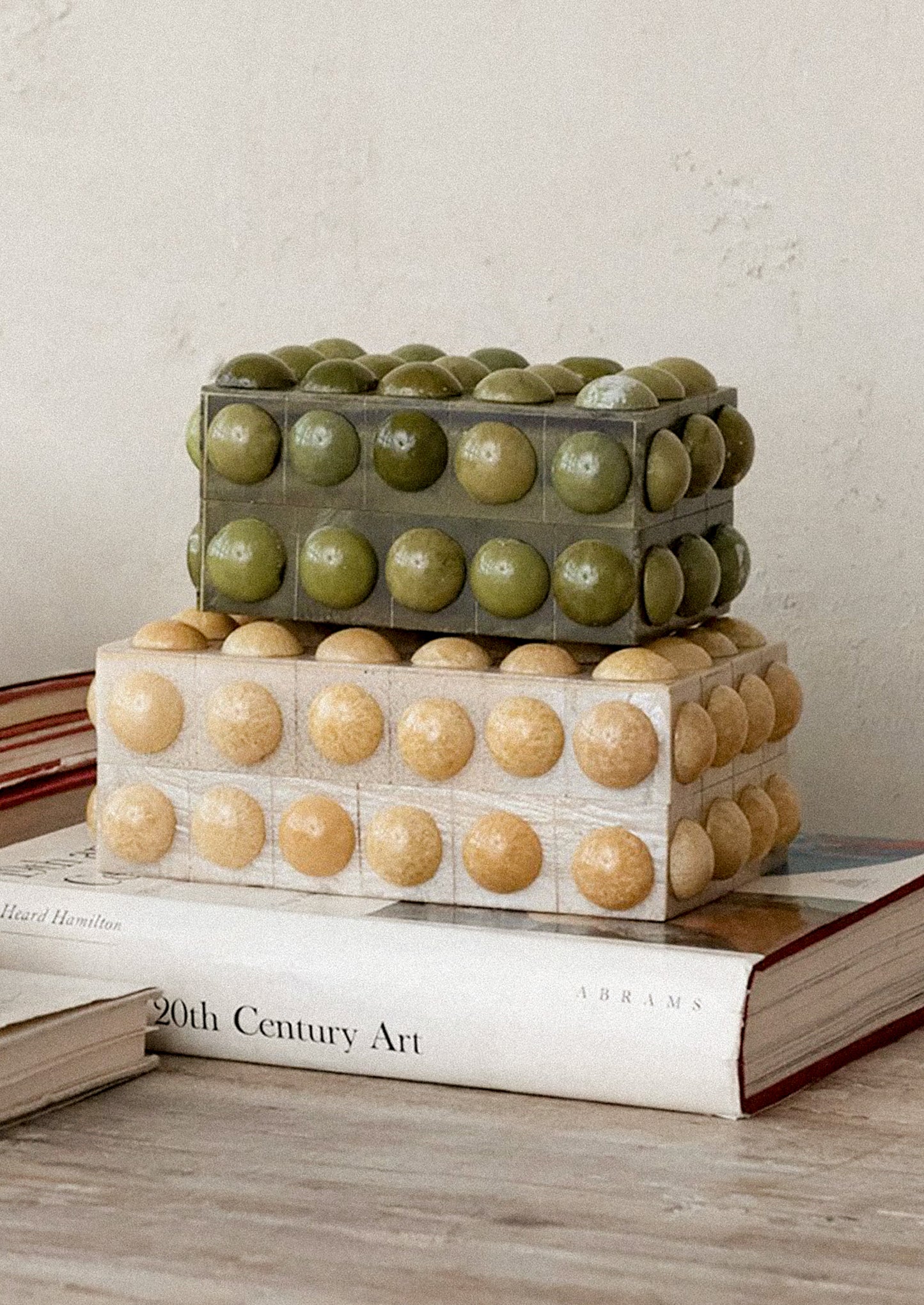 Decorative boxes with hobnail texture stacked on top of each other on a book.
